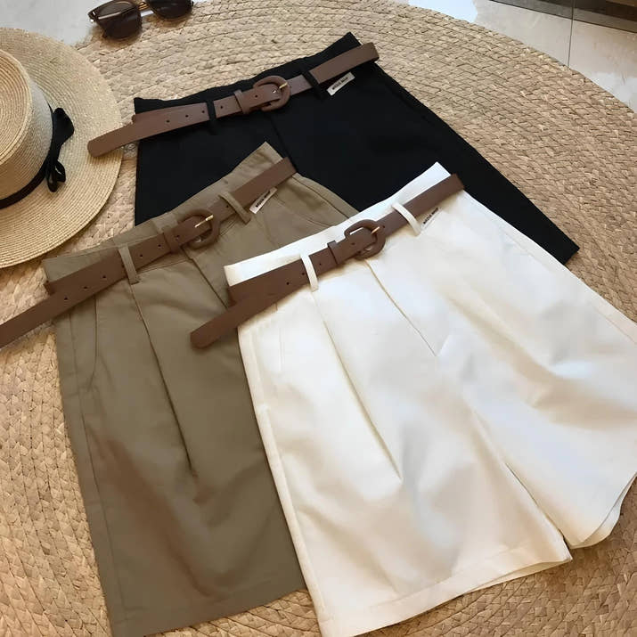 Woman wearing high-waisted cotton shorts with a tucked-in blouse, walking outdoors in summer.