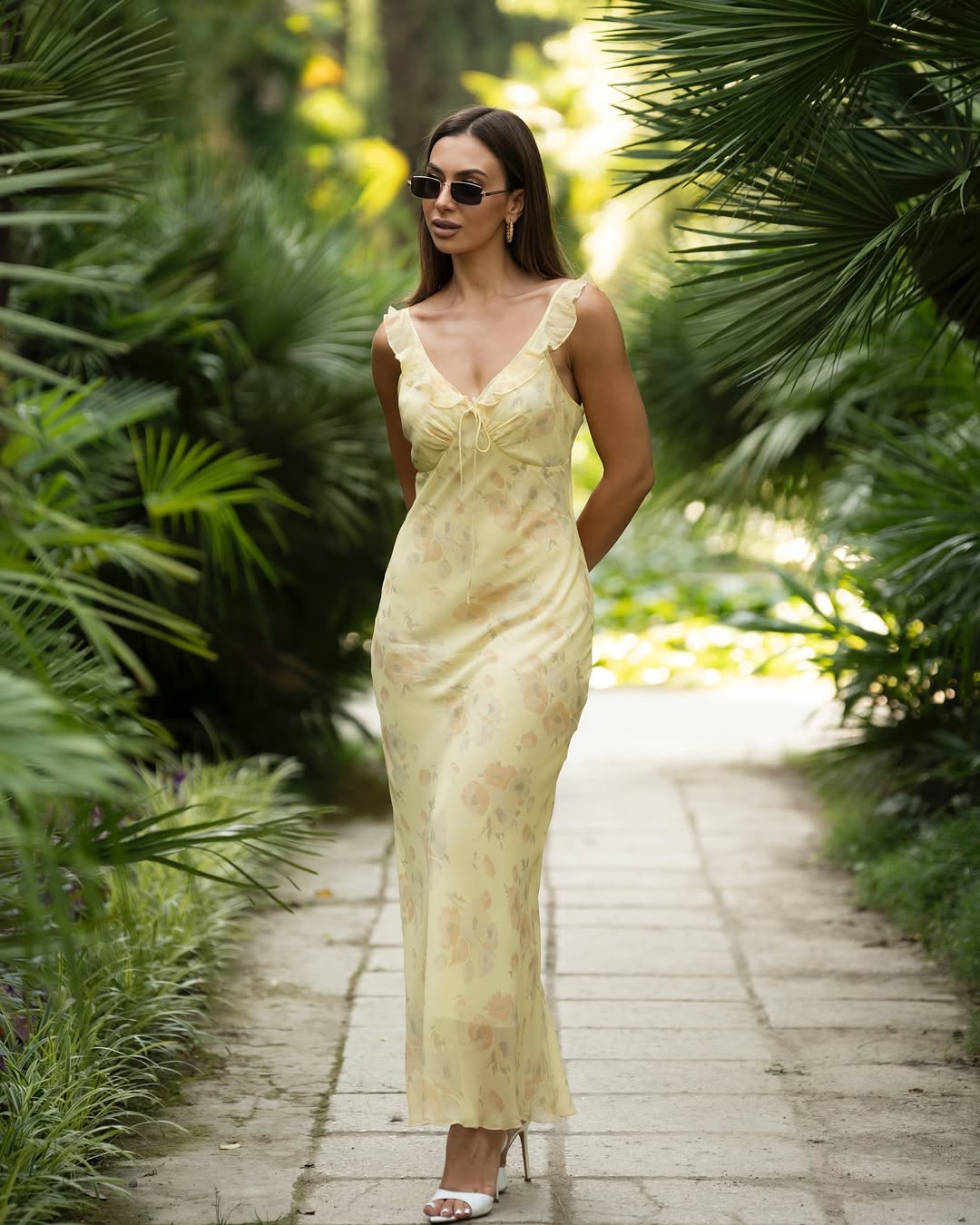 Woman in a yellow dress walking through a tropical garden