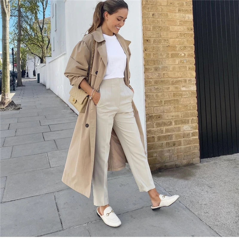 Woman walking confidently in tailored high-waisted slim pants, paired with a tucked-in blouse and loafers, showing elegant everyday style.