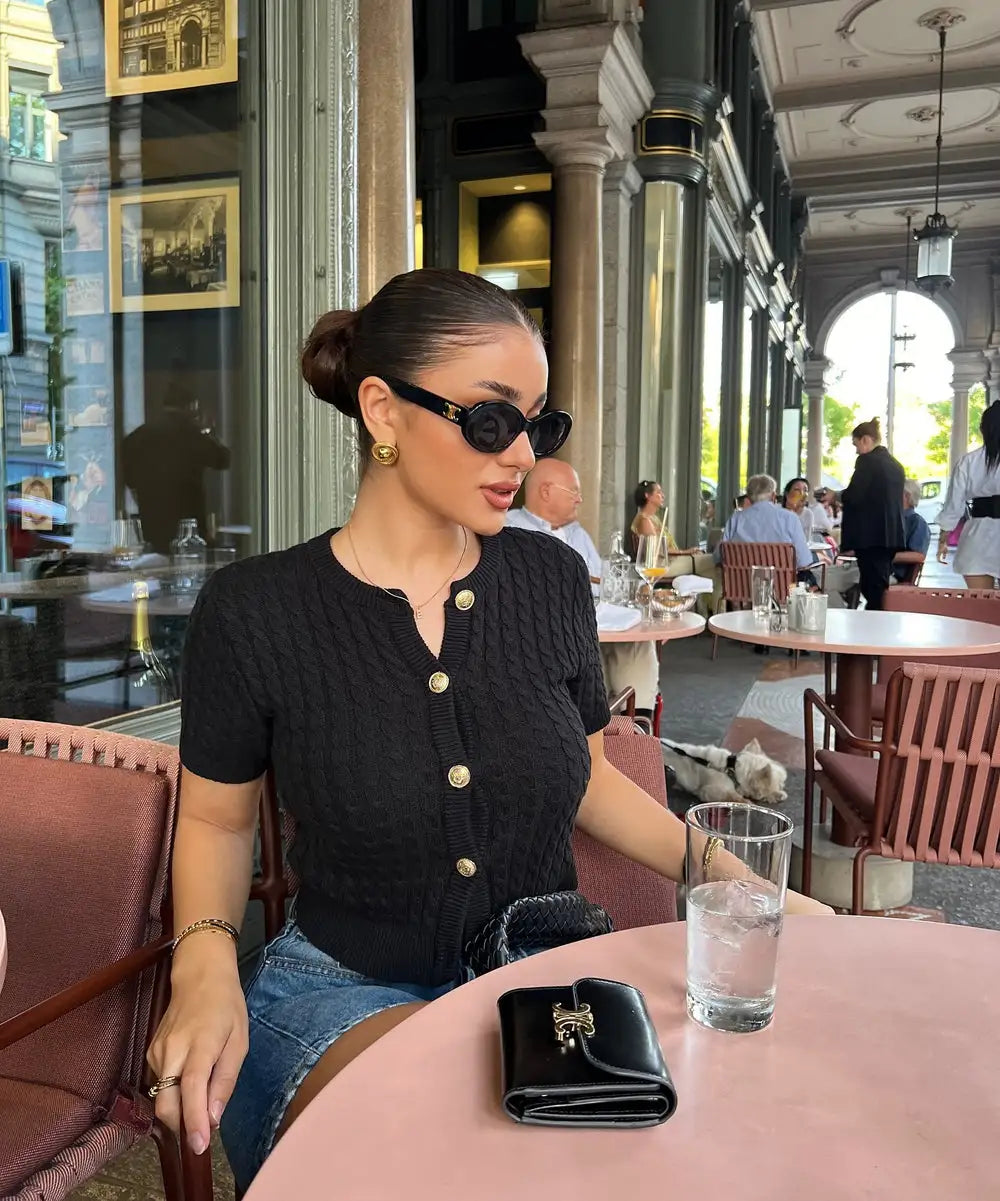 Woman wearing a slim fit solid color short sleeved knit cardigan, styled for autumn casual outings.