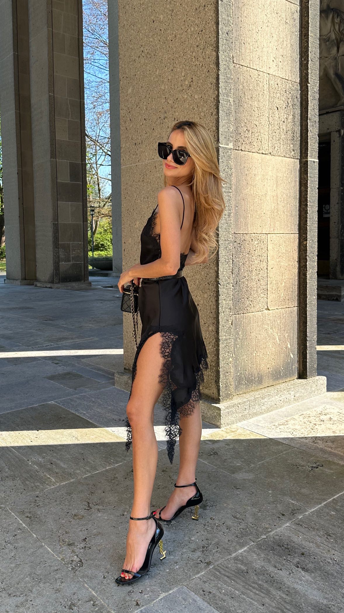 Woman in a black dress standing outdoors near stone columns