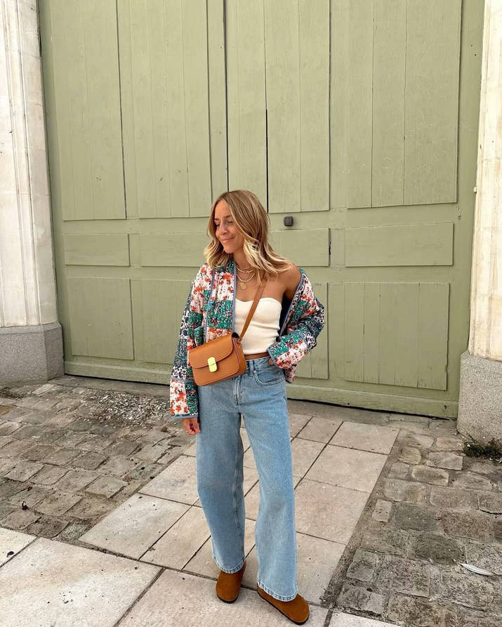 Woman walking outdoors in fall wearing a quilted patchwork floral jacket in orange tones.