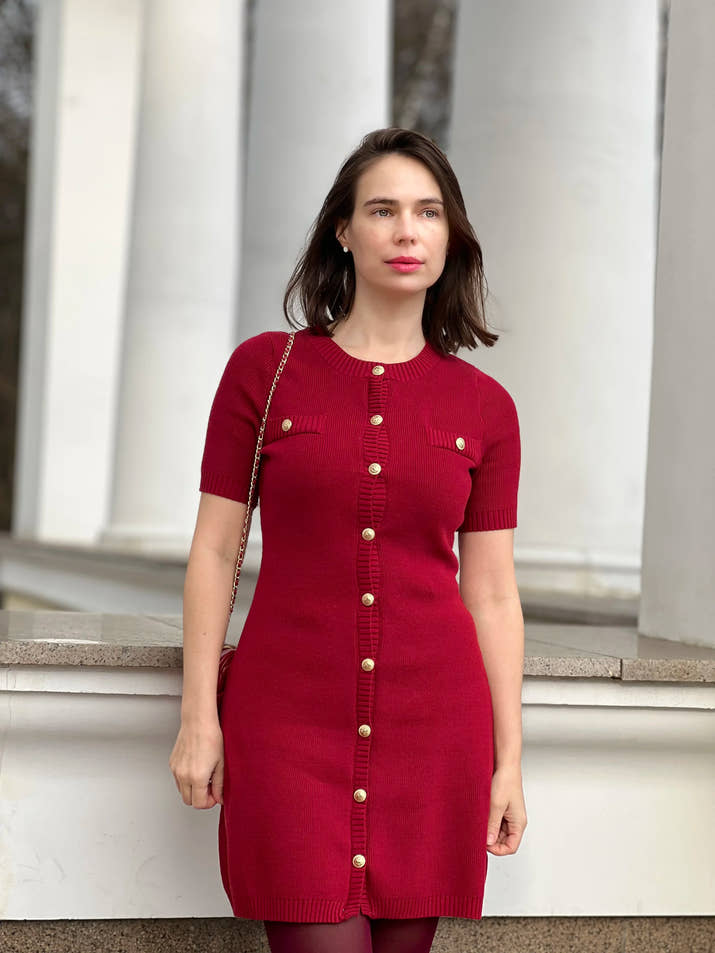 Confident woman walking downtown in a fitted ribbed knit mini dress with metal buttons, styled with sunglasses and ankle boots.