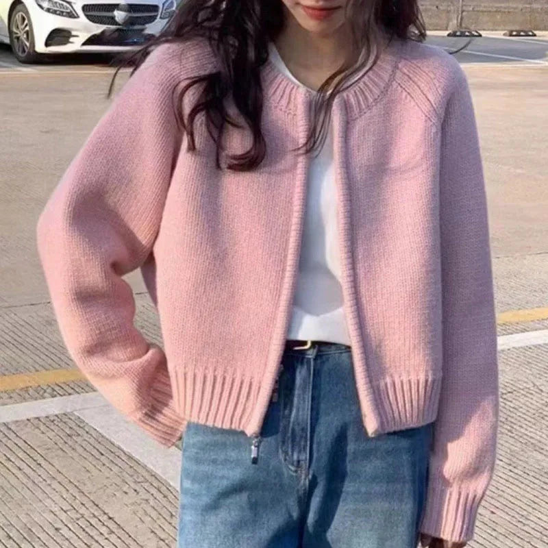 Person wearing a pink sweater and blue jeans on a road.