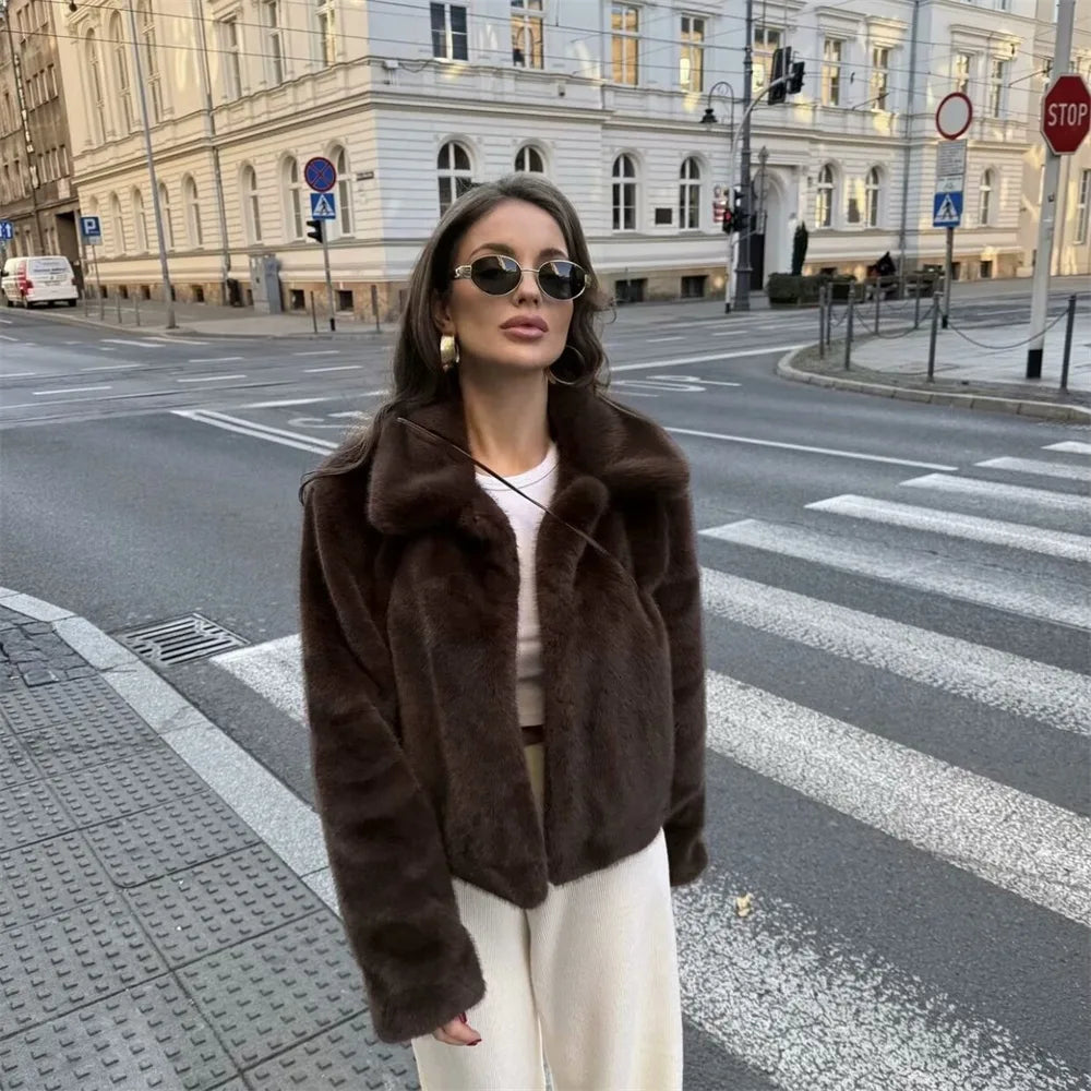 Woman wearing a brown faux fur winter jacket while sipping coffee outside a cozy café in cold weather.