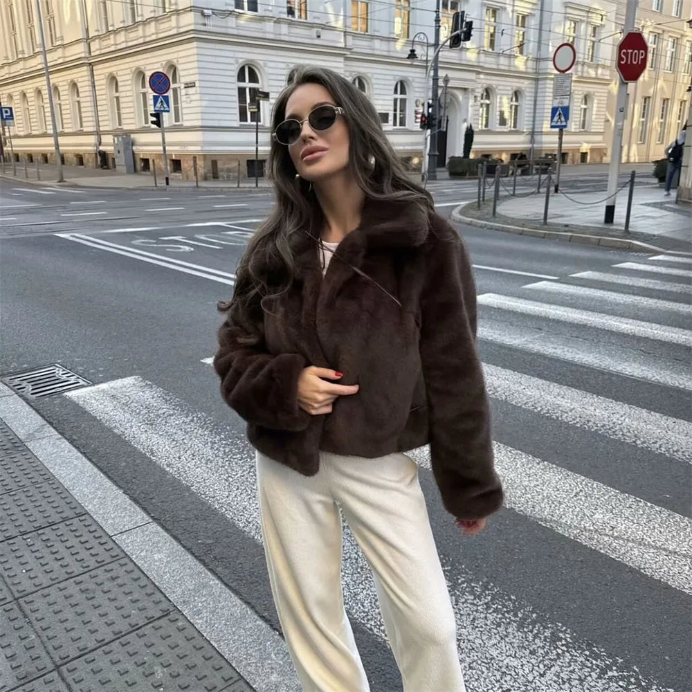 Woman wearing a brown faux fur winter jacket while sipping coffee outside a cozy café in cold weather.