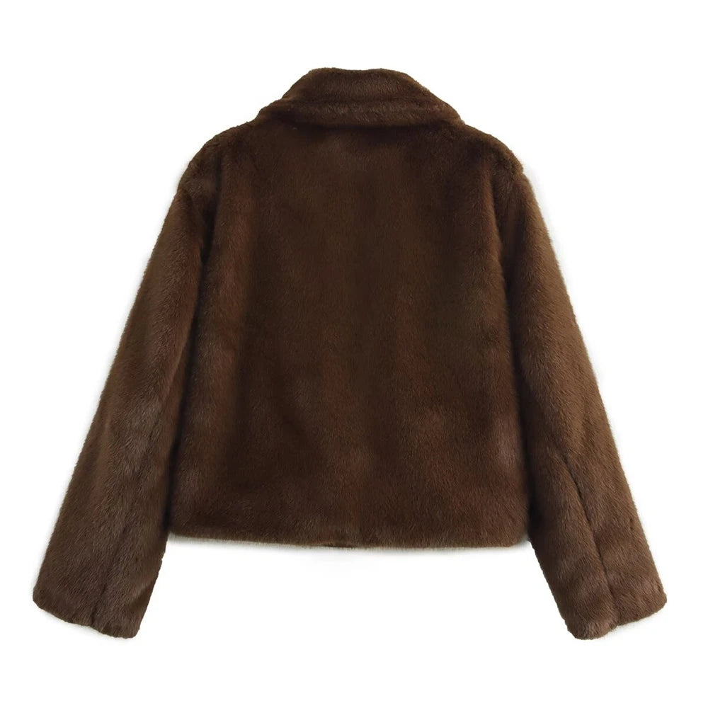 Woman wearing a brown faux fur winter jacket while sipping coffee outside a cozy café in cold weather.