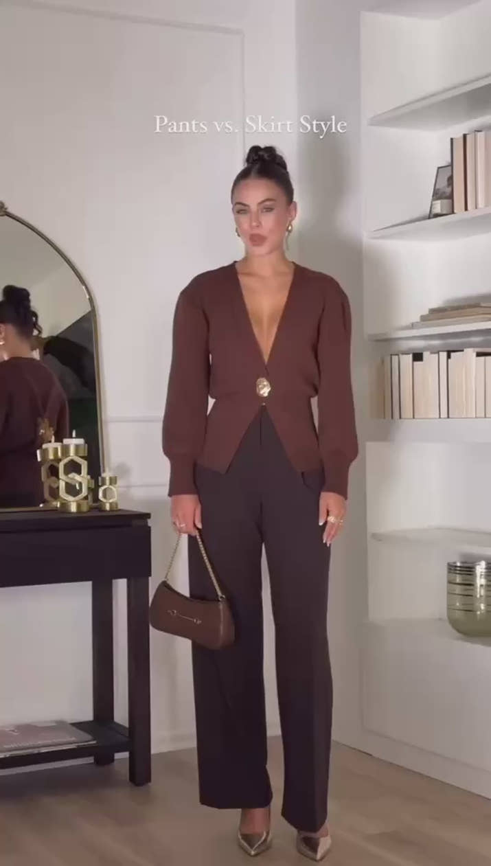 Model wearing a V-neck knit cardigan over a white tank top and trousers, enjoying a coffee outdoors in spring.