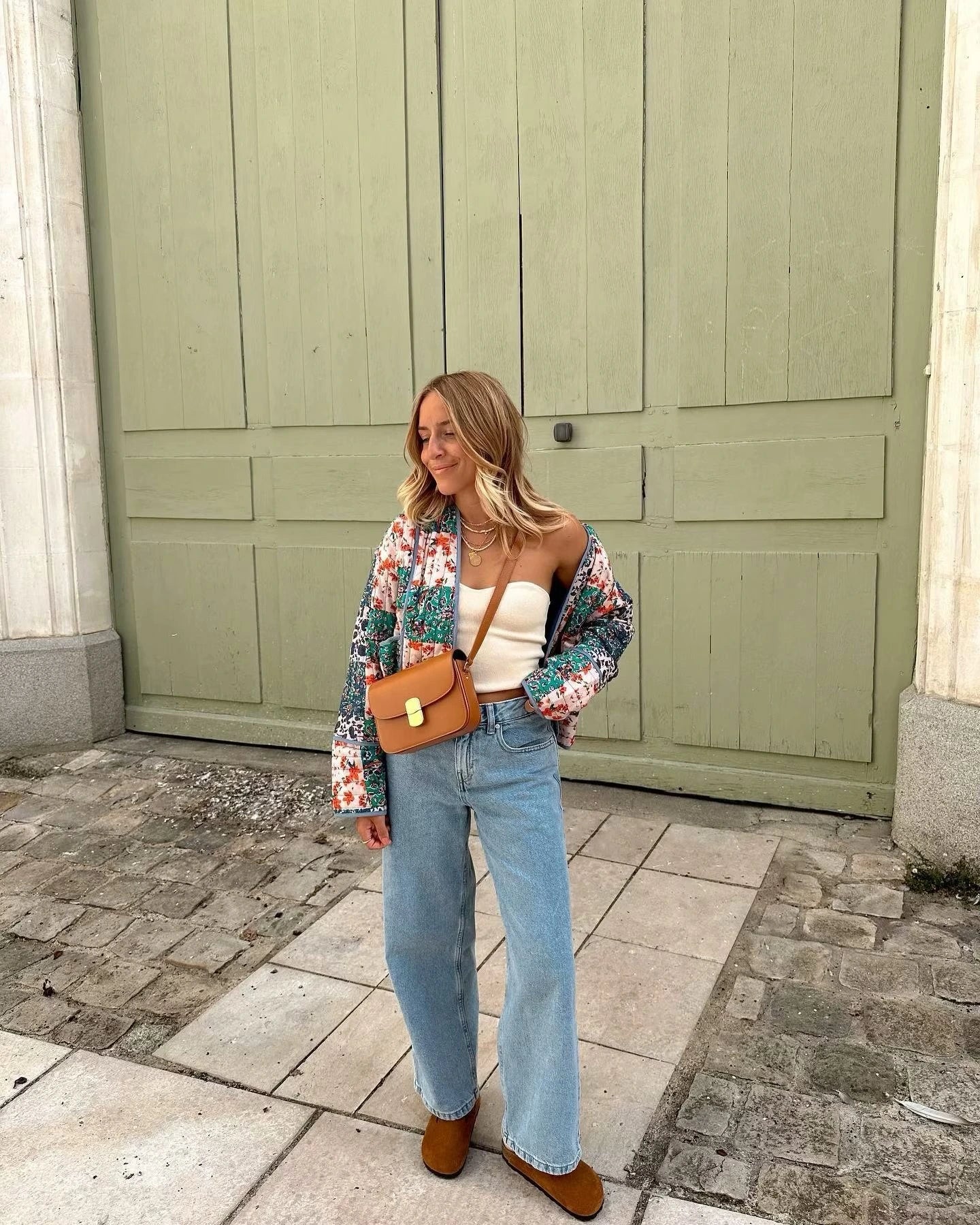 Woman walking outdoors in fall wearing a quilted patchwork floral jacket in orange tones.