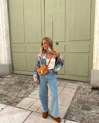 Woman walking outdoors in fall wearing a quilted patchwork floral jacket in orange tones.