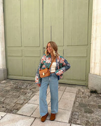 Woman walking outdoors in fall wearing a quilted patchwork floral jacket in orange tones.