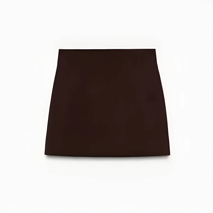 Woman wearing a slim-fit brown blazer jacket and A-line mini skirt in an office setting, confidently presenting in a modern workspace.