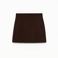 Woman wearing a slim-fit brown blazer jacket and A-line mini skirt in an office setting, confidently presenting in a modern workspace.