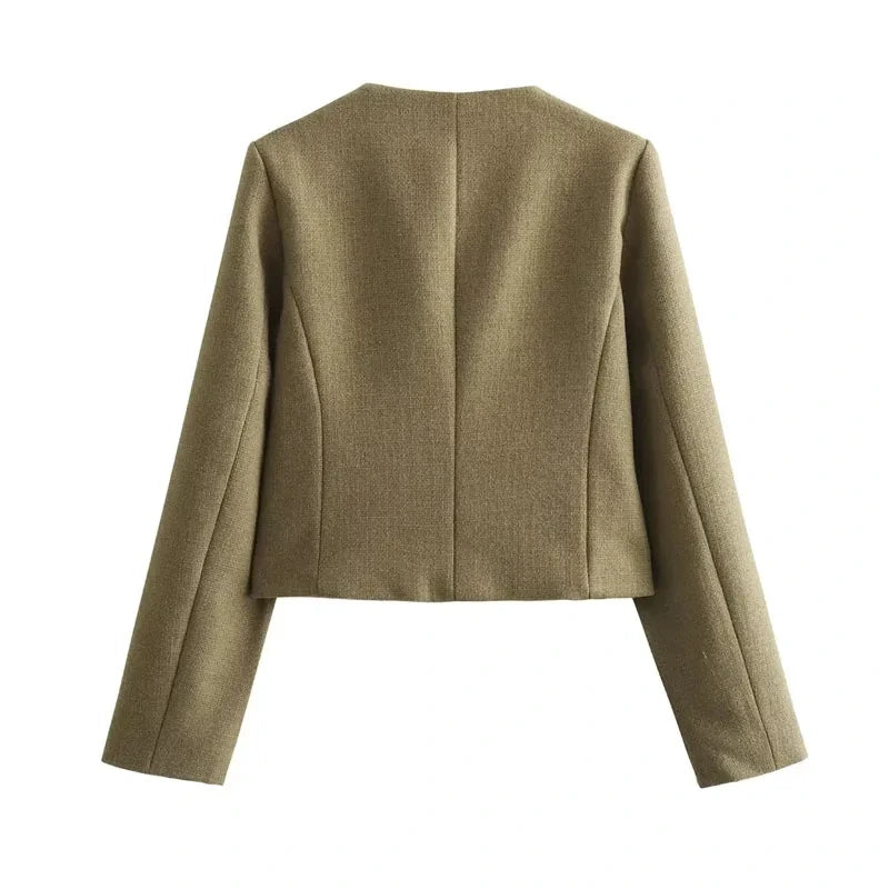 The woman looks casual and chic while walking around the city in a lightly cut khaki double-breasted tweed jacket with buttons.