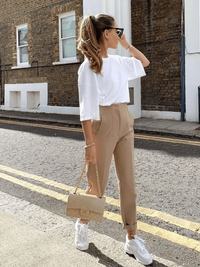 Woman walking confidently in tailored high-waisted slim pants, paired with a tucked-in blouse and loafers, showing elegant everyday style.