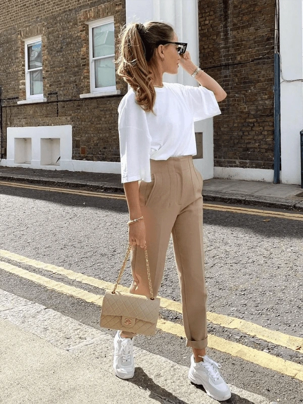 Woman walking confidently in tailored high-waisted slim pants, paired with a tucked-in blouse and loafers, showing elegant everyday style.