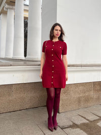 Confident woman walking downtown in a fitted ribbed knit mini dress with metal buttons, styled with sunglasses and ankle boots.