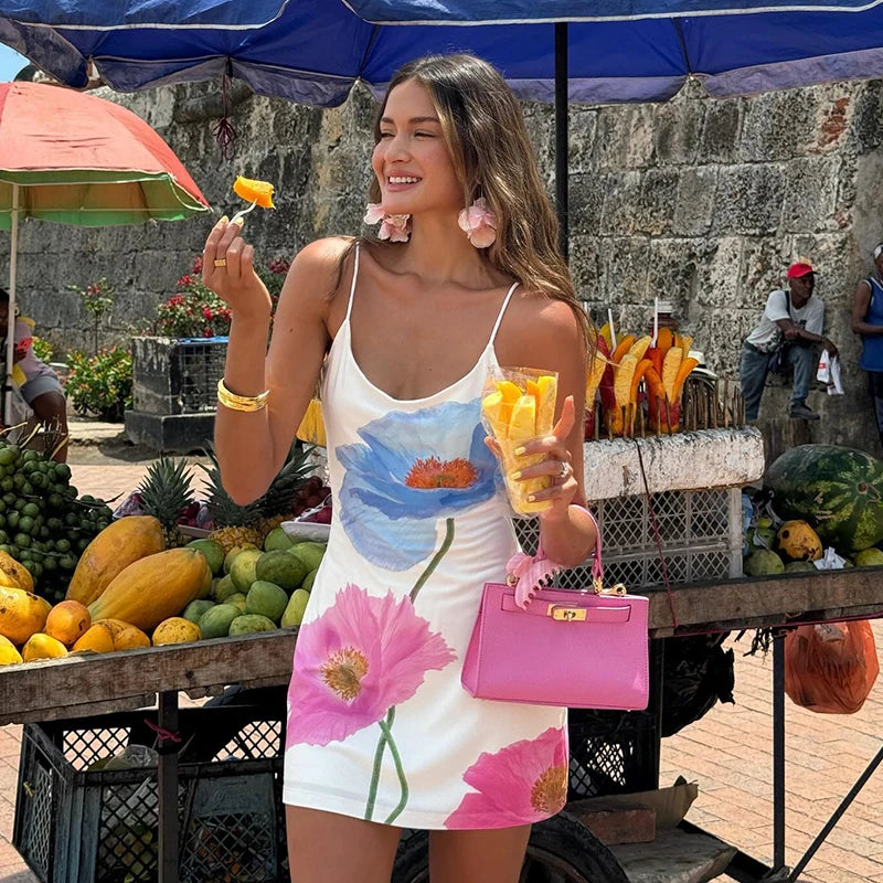 Woman in a floral dress holding fruit at an outdoor market.