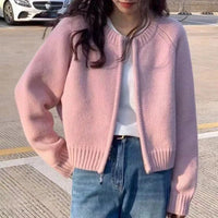 Person wearing a pink sweater and blue jeans on a road.