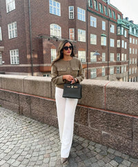 The woman looks casual and chic while walking around the city in a lightly cut khaki double-breasted tweed jacket with buttons.