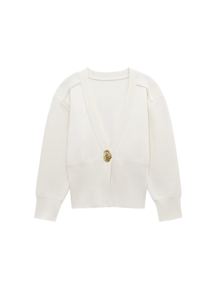 Model wearing a V-neck knit cardigan over a white tank top and trousers, enjoying a coffee outdoors in spring.