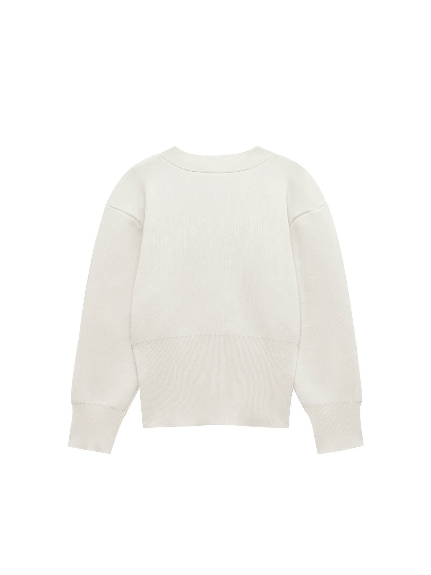 Model wearing a V-neck knit cardigan over a white tank top and trousers, enjoying a coffee outdoors in spring.