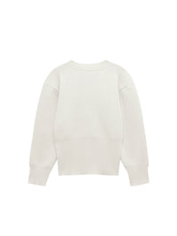 Model wearing a V-neck knit cardigan over a white tank top and trousers, enjoying a coffee outdoors in spring.