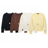 Model wearing a V-neck knit cardigan over a white tank top and trousers, enjoying a coffee outdoors in spring.