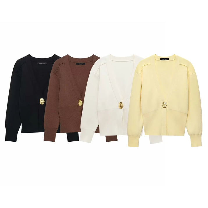 Model wearing a V-neck knit cardigan over a white tank top and trousers, enjoying a coffee outdoors in spring.