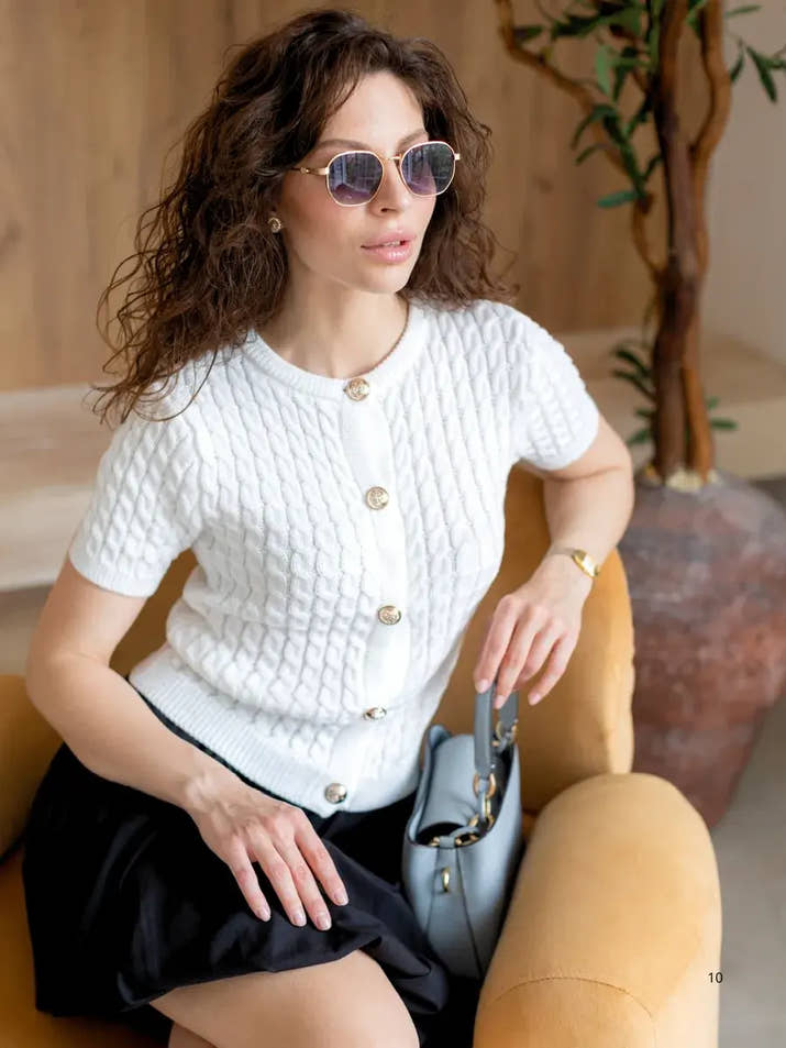 Woman wearing a slim fit solid color short sleeved knit cardigan, styled for autumn casual outings.