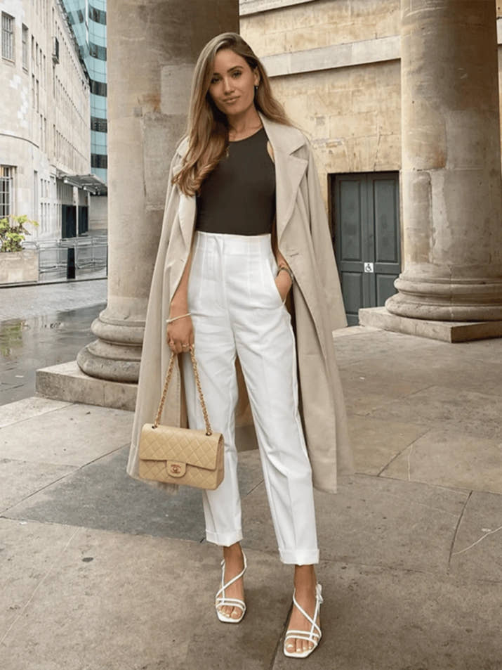 Woman walking confidently in tailored high-waisted slim pants, paired with a tucked-in blouse and loafers, showing elegant everyday style.