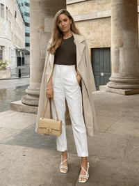 Woman walking confidently in tailored high-waisted slim pants, paired with a tucked-in blouse and loafers, showing elegant everyday style.