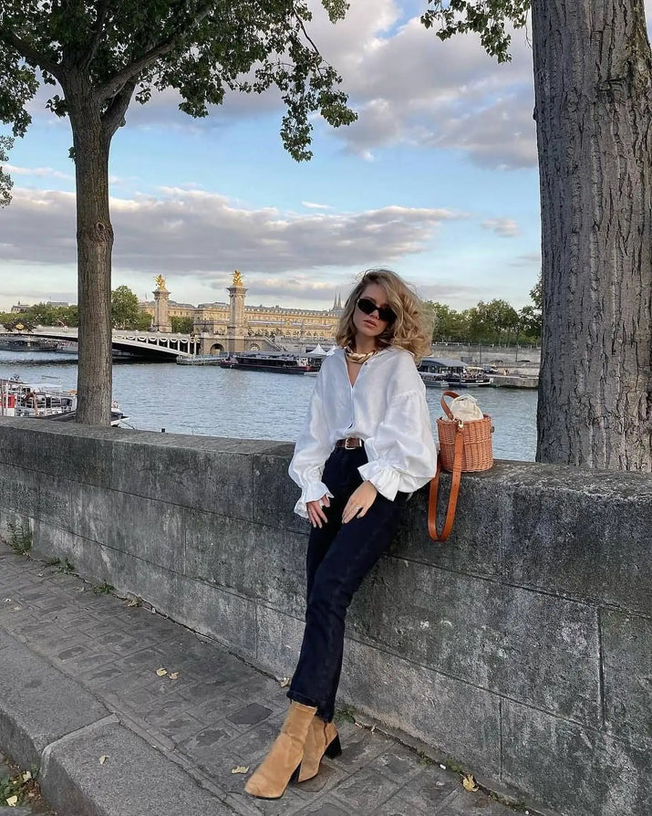 Model wearing white puff sleeve blouse with denim shorts, standing outdoors on a sunny day.