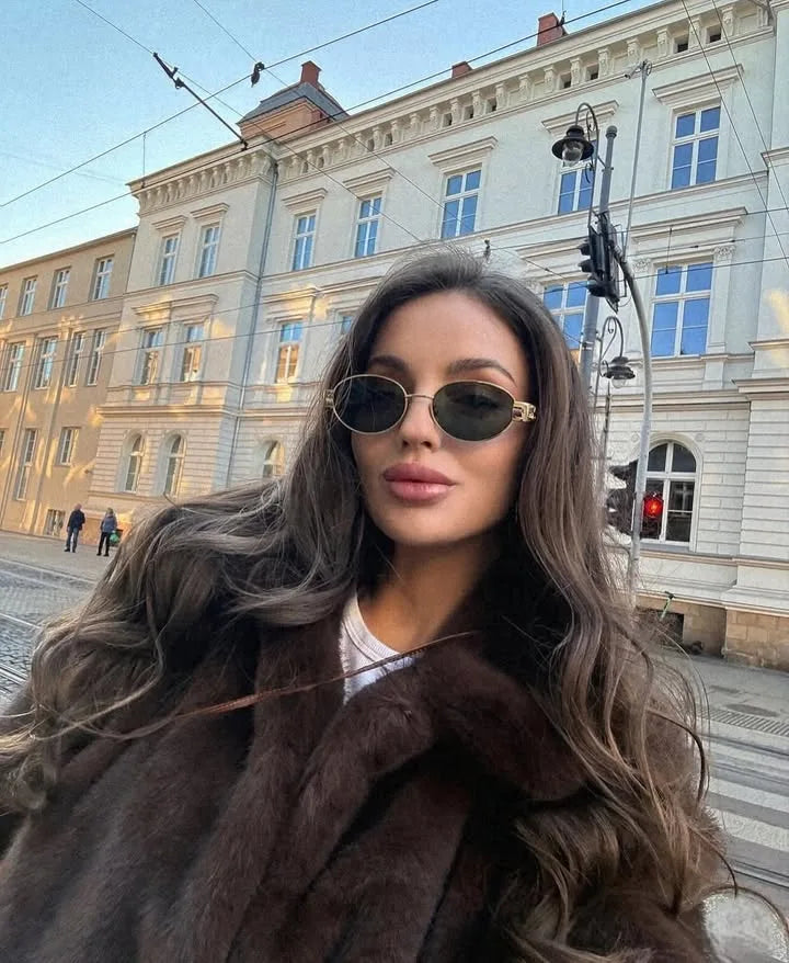 Woman wearing a brown faux fur winter jacket while sipping coffee outside a cozy café in cold weather.