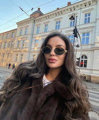 Woman wearing a brown faux fur winter jacket while sipping coffee outside a cozy café in cold weather.