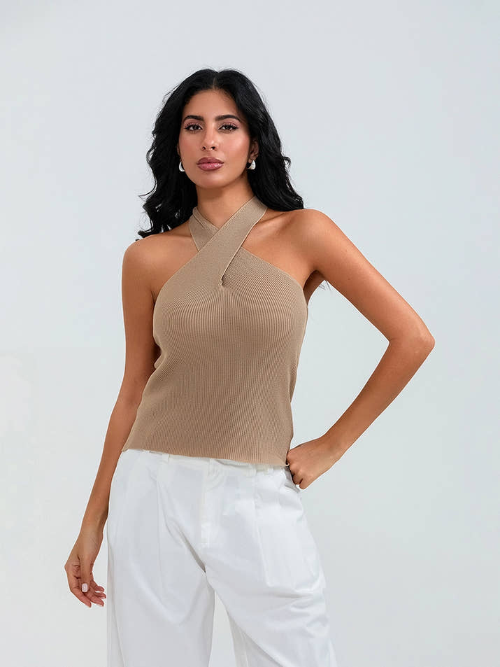 Model wearing khaki cross-front knit tank top with white cargo pants and sneakers, walking through a sunny urban street.