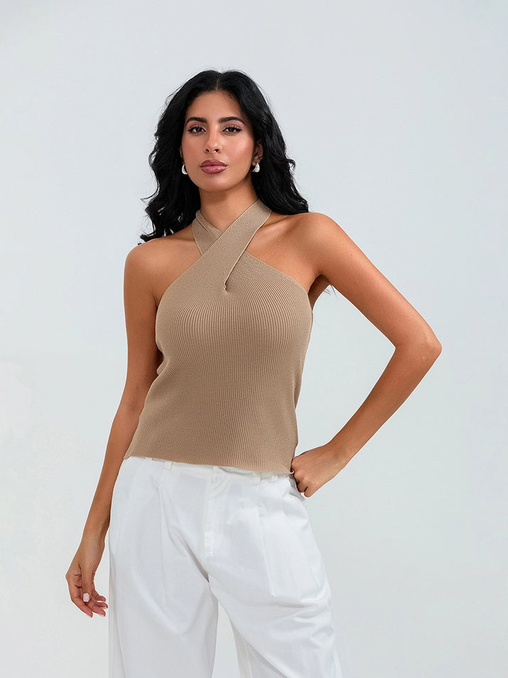 Model wearing khaki cross-front knit tank top with white cargo pants and sneakers, walking through a sunny urban street.