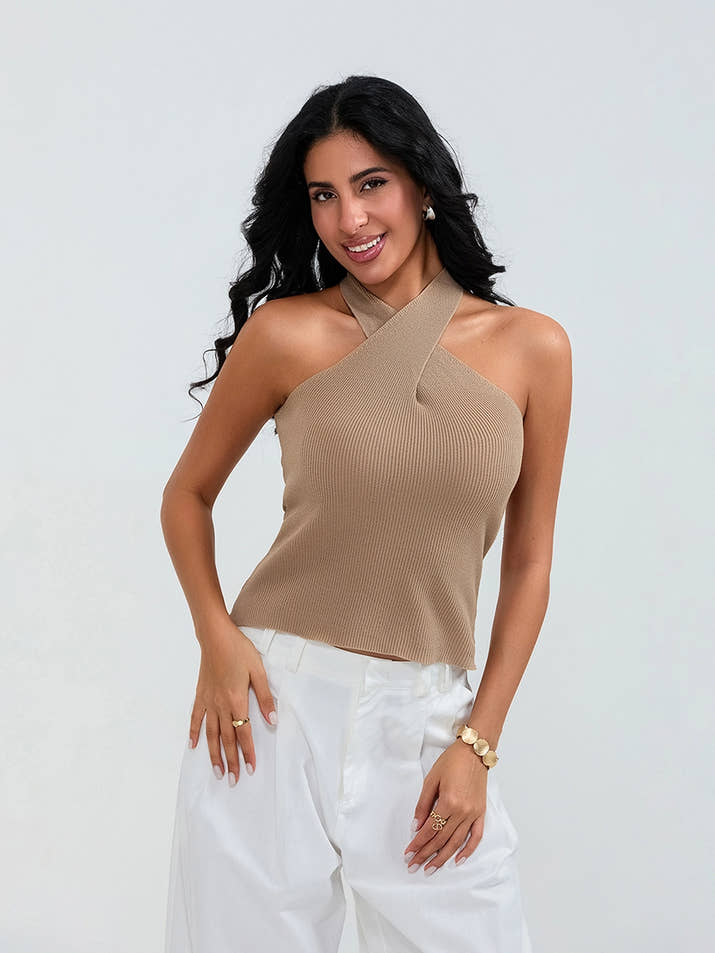 Model wearing khaki cross-front knit tank top with white cargo pants and sneakers, walking through a sunny urban street.