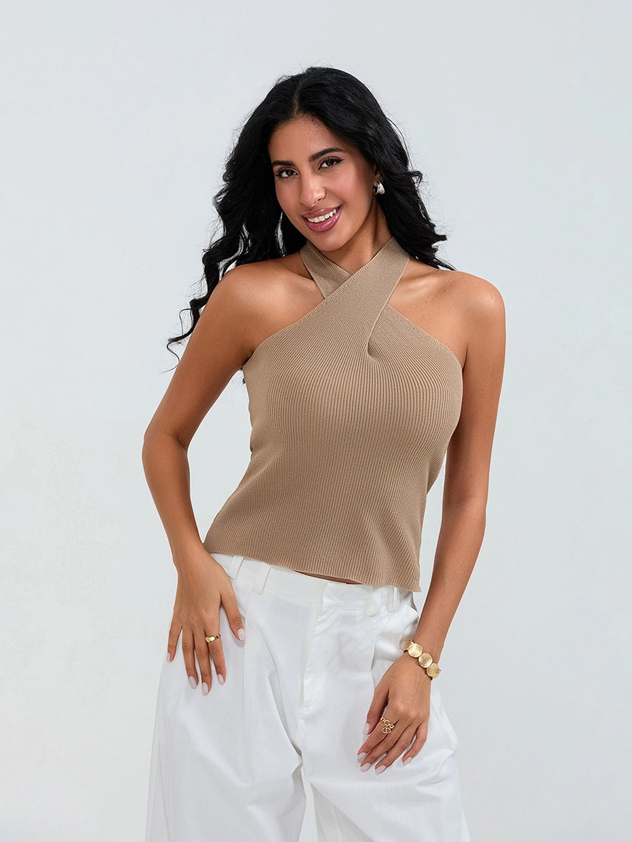 Model wearing khaki cross-front knit tank top with white cargo pants and sneakers, walking through a sunny urban street.