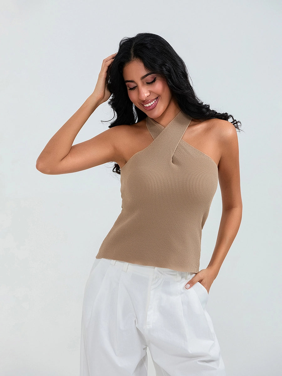 Model wearing khaki cross-front knit tank top with white cargo pants and sneakers, walking through a sunny urban street.