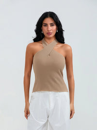 Model wearing khaki cross-front knit tank top with white cargo pants and sneakers, walking through a sunny urban street.