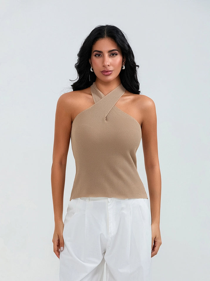 Model wearing khaki cross-front knit tank top with white cargo pants and sneakers, walking through a sunny urban street.