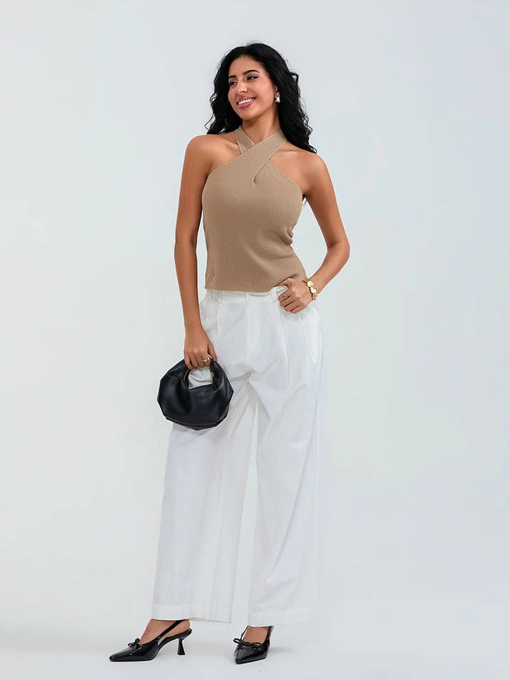 Model wearing khaki cross-front knit tank top with white cargo pants and sneakers, walking through a sunny urban street.