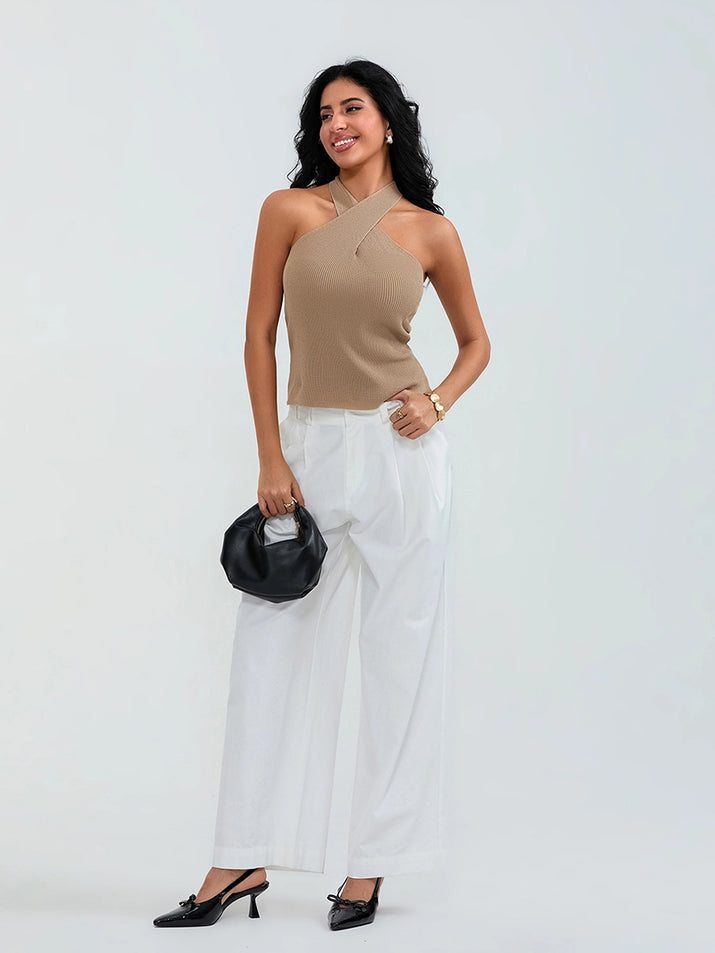 Model wearing khaki cross-front knit tank top with white cargo pants and sneakers, walking through a sunny urban street.