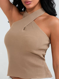 Model wearing khaki cross-front knit tank top with white cargo pants and sneakers, walking through a sunny urban street.