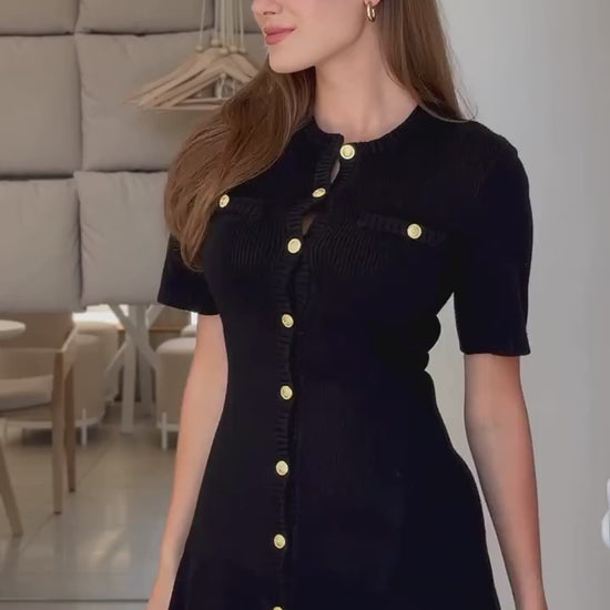 Confident woman walking downtown in a fitted ribbed knit mini dress with metal buttons, styled with sunglasses and ankle boots.