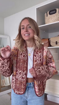 Woman walking outdoors in fall wearing a quilted patchwork floral jacket in orange tones.