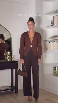 Model wearing a V-neck knit cardigan over a white tank top and trousers, enjoying a coffee outdoors in spring.