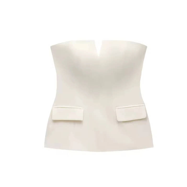 Woman wearing a strapless off white backless crop top, styled for office and club look.